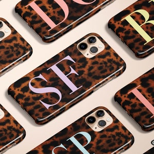 May include: A set of eight iPhone cases with a leopard print design and a single letter in a pastel color on each case. The letters are D, B, S, L, P, I, Z, and G.