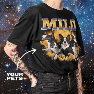 May include: Black t-shirt with a yellow and orange graphic of four dogs. The dogs are a corgi, a border collie, and two other dogs. The text "MILO" is printed in yellow and blue letters on the shirt.