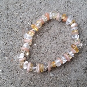 May include: A bracelet made of small, irregular shaped stones in shades of white, peach, and yellow.