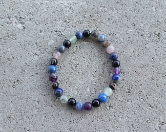 May include: A multi-colored beaded bracelet with blue, black, purple, and green beads.