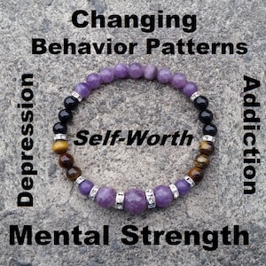 May include: A purple, black, and brown beaded bracelet with silver accents. The bracelet is on a gray background with the words "Self-Worth", "Changing Behavior Patterns", "Depression", "Addiction", and "Mental Strength" written around it.