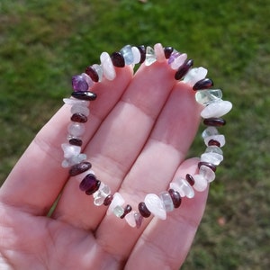 Op de afbeelding: Een armband gemaakt van kleine, onregelmatig gevormde stenen in tinten roze, wit, groen en paars.