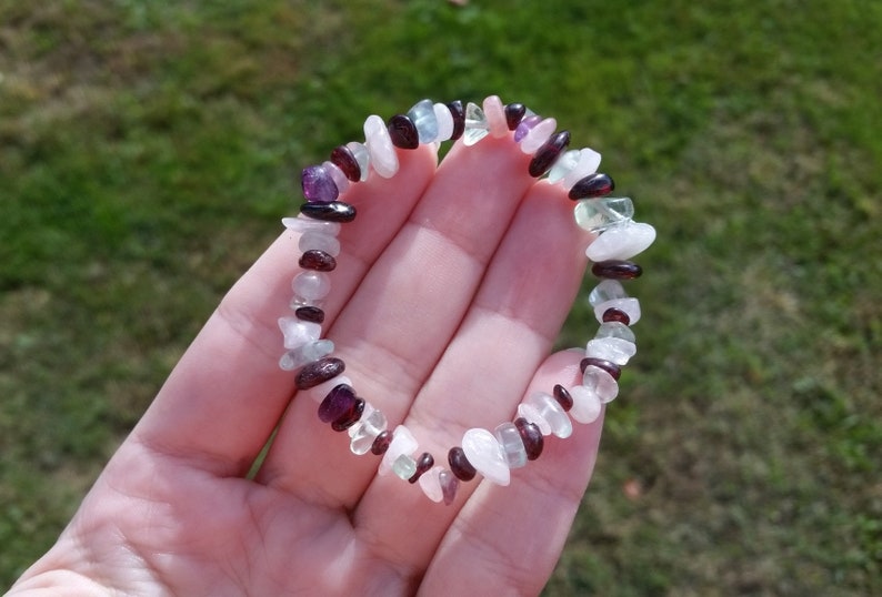 Op de afbeelding: Een armband gemaakt van kleine, onregelmatig gevormde stenen in tinten roze, wit, groen en paars.