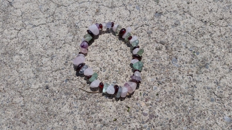Op de afbeelding: Een armband gemaakt van roze, groene en rode edelsteen kralen.