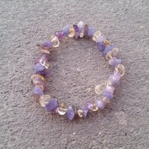 May include: A purple and yellow gemstone bracelet with small, irregular shaped stones.