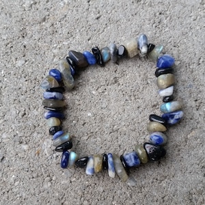 May include: A bracelet made of blue, black, and brown stones. The stones are irregularly shaped and strung together on a clear elastic cord.