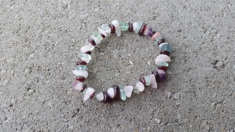 Op de afbeelding: Een veelkleurige edelsteen armband met roze, groene en rode stenen. De armband is gemaakt van kleine, onregelmatig gevormde stenen.