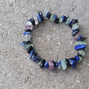 May include: A bracelet made of blue, green, black, and purple gemstone beads. The bracelet is made of natural stones and is a beautiful piece of jewelry.