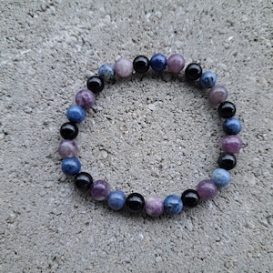 May include: A beaded bracelet with blue, purple, and black beads. The bracelet is made of natural stones and is designed to be worn on the wrist.