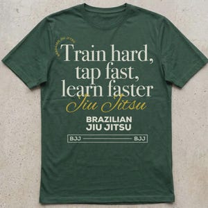 May include: Green t-shirt with the text "Train hard, tap fast, learn faster Jiu Jitsu" in white and gold lettering. The words "Brazilian Jiu Jitsu" are printed below the text in white. The shirt also has the letters "BJJ" printed on the bottom.