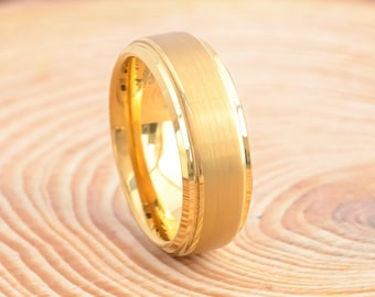 May include: A gold-colored wedding band with a brushed finish and a beveled edge.