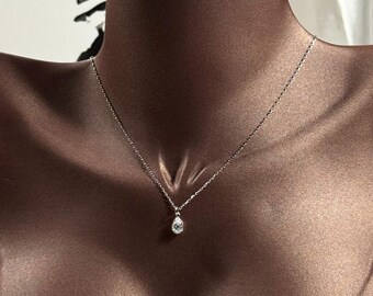 May include: A silver chain necklace with a teardrop-shaped pendant featuring a clear crystal.