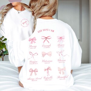 May include: White sweatshirt with pink bows and the text "GOD SAYS I AM" with bible verses listed below each bow.