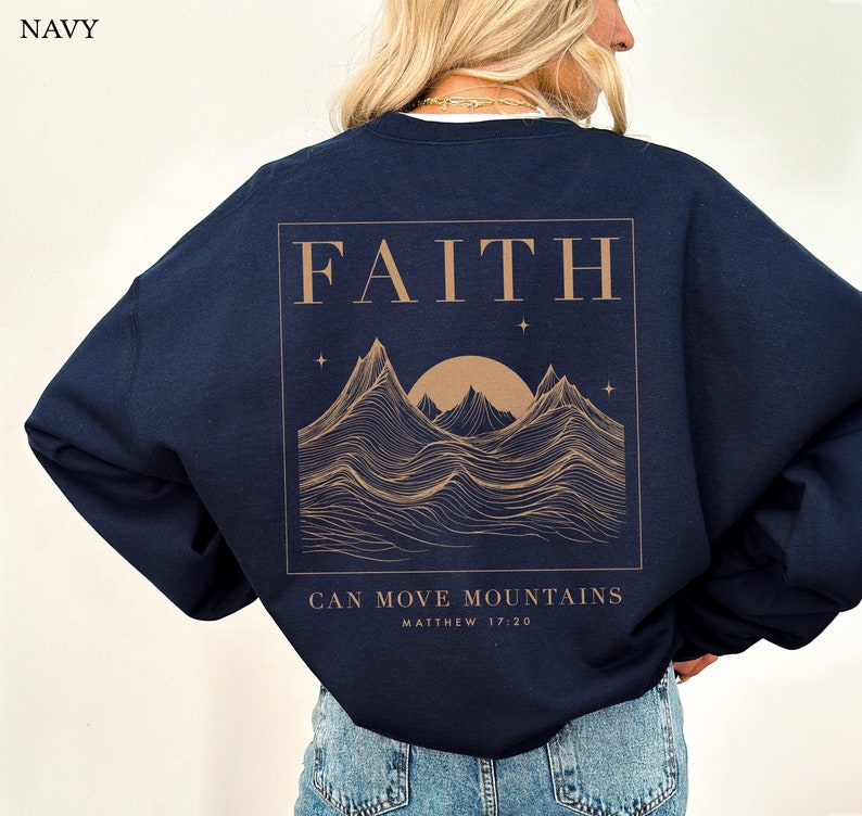 May include: Navy blue sweatshirt with a graphic print of mountains, a sun, and stars. The text "FAITH CAN MOVE MOUNTAINS MATTHEW 17:20" is printed on the sweatshirt.