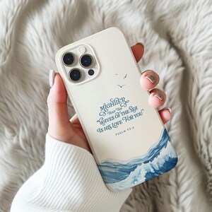 May include: White phone case with a blue and white ocean wave design. The text "MIGHTER THAN THE WAVES OF THE SEA IS HIS LOVE FOR YOU" is printed on the case, along with "PSALM 93:4".