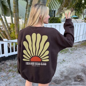 May include: A brown sweatshirt with a yellow and orange sun graphic and the text "THE SUN WILL RISE PSALM 30:5".
