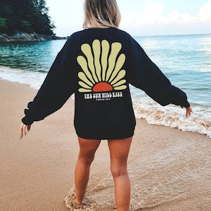 May include: Black sweatshirt with a yellow and red sun graphic and the text "THE SUN WILL RISE, PSALM 30:5".