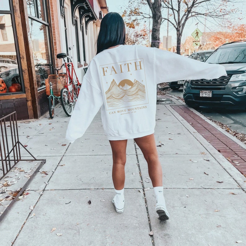 May include: White sweatshirt with a gold graphic of mountains and the text "FAITH CAN MOVE MOUNTAINS Matthew 17:20".