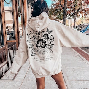 May include: A cream-colored hoodie with a black floral design and the text "His mercies are new every morning Lamentations 3:22-23".