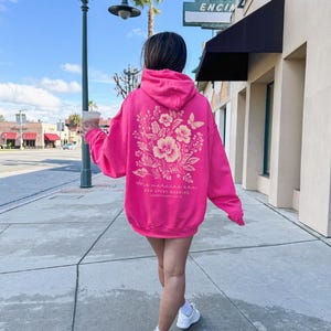 May include: A pink hoodie with a floral design and the text "The mercies are new every morning" on the back.