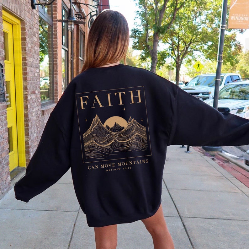 May include: Black sweatshirt with a gold graphic of mountains and a sun with the text "FAITH CAN MOVE MOUNTAINS MATTHEW 17:20"