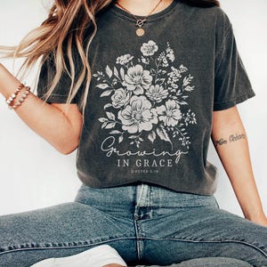 May include: A dark gray t-shirt with a floral design and the text "Growing in Grace 2 Peter 3:18".