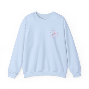 May include: Light blue sweatshirt with a pink and white graphic design that says "God is within reach, the will not fail".