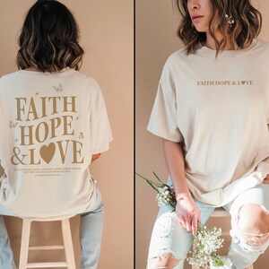 May include: A beige oversized t-shirt with the text "FAITH HOPE & LOVE" printed in brown on the front and the same text with a heart and butterflies printed in brown on the back.