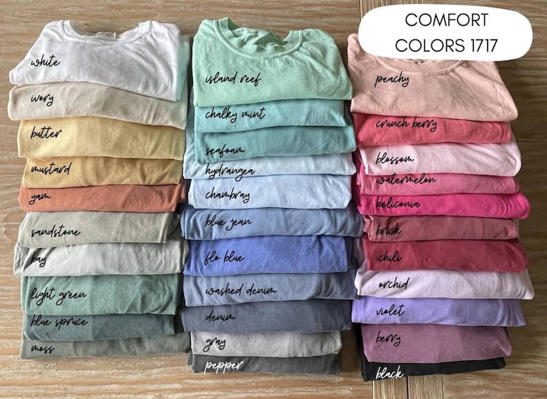Puede incluir: Una colecci&oacute;n de 24 camisetas de varios colores, apiladas en filas. Los colores est&aacute;n etiquetados con nombres como "blanco", "marfil", "mantequilla", "mostaza", "yam", "piedra arenisca", "bah&iacute;a", "verde claro", "abeto azul", "musgo", "arrecife de isla", "menta cremosa", "espuma de mar", "hortensia", "chambray", "jean azul", "flo blue", "denim lavado", "denim", "gris", "pimienta", "melocot&oacute;n", "baya crujiente", "flor", "sand&iacute;a", "heliconia", "ladrillo", "chile", "orqu&iacute;dea", "violeta", "baya" y "negro".