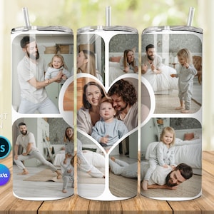 May include: A white tumbler with a collage of family photos. The photos show a family of four, including two parents and two children. The photos are arranged in a heart shape in the center of the tumbler. The tumbler has a silver lid and a straw.