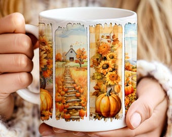 May include: White ceramic mug featuring a fall-themed design. The design includes sunflowers, pumpkins, a barn, and a wooden pathway. The mug is held by a person wearing a white sweater.