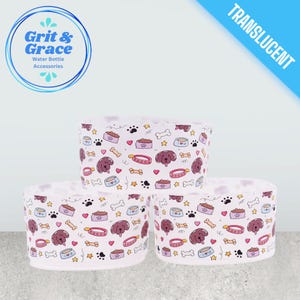 Può includere: Tre accessori bianchi per bottiglie d'acqua con un motivo ripetuto di facce di cani, impronte di zampe, ossa, ciotole per cibo e collari. Gli accessori hanno il testo "Grit & Grace Water Bottle Accessories" e la parola "TRANSLUCENT".