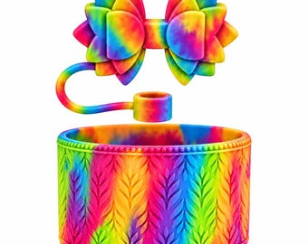 May include: A tie-dye silicone boot for a tumbler featuring a textured leaf pattern and a beaded top edge. A matching tie-dye bow-shaped straw topper is connected to a small ring, showcasing a vibrant rainbow color palette throughout.