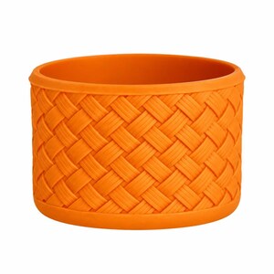 May include: A bright orange silicone sleeve featuring a raised, textured basketweave pattern across the exterior. The cylindrical accessory has a smooth, solid rim at the top and bottom, designed to fit snugly around a container or tumbler.