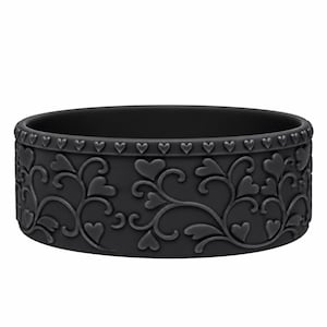 May include: A matte black silicone ring featuring a raised, embossed pattern of swirling vines and small heart shapes. The top edge of the band is decorated with a continuous row of tiny, repeating heart icons encircling the entire circumference.
