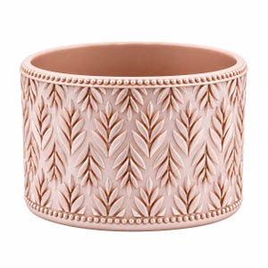May include: A cylindrical blush pink planter featuring a repeating embossed leaf pattern across the exterior surface. The top and bottom edges are finished with a decorative beaded border, providing a textured detail to the vessel.