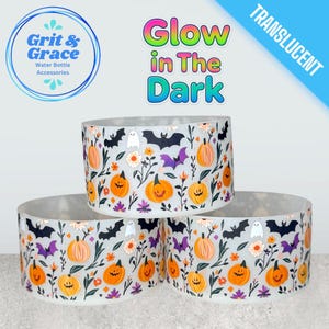 Può includere: Tre accessori traslucidi per bottiglie d'acqua a tema Halloween. Ogni accessorio è decorato con zucche arancioni, pipistrelli, fantasmi e fiori. Il testo "Glow in The Dark" è visibile sopra gli accessori.