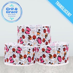 Può includere: Tre accessori traslucidi per bottiglie d'acqua con sfondo bianco, adornati da un motivo ripetuto di farfalle rosa, coccinelle arancioni, api gialle e margherite bianche. Il logo blu in alto a sinistra recita "Grit & Grace Water Bottle Accessories."