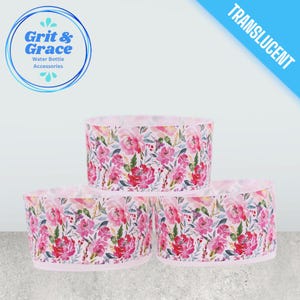 Può includere: Tre accessori traslucidi per bottiglie d'acqua con un motivo floreale di fiori rosa e rossi e foglie verdi. Gli accessori sono cilindrici e hanno un bordo rosa chiaro. L'immagine include anche il testo "Grit & Grace Water Bottle Accessories".