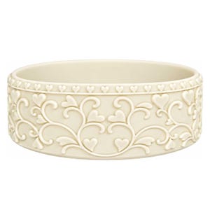 Puede incluir: Un cuenco redondo de color blanco roto con un patrón en relieve de enredaderas y pequeños corazones en el exterior. Un borde continuo de diminutos corazones rodea la parte superior del cuenco, creando un diseño con textura en relieve.