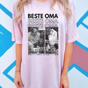Puede incluir: Camiseta rosa claro con las palabras "BESTE OMA" repetidas tres veces en negro. La camiseta presenta un collage de fotos en blanco y negro y el texto "EST. 2022".