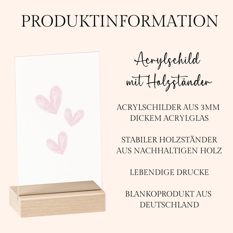 May include: A clear acrylic sign with three pink hearts, displayed on a natural wood base. The sign features the text "PRODUKTINFORMATION" and other German text. The product is made in Germany.