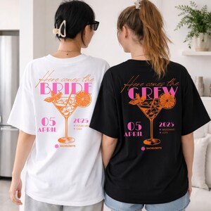 May include: Two oversized t-shirts, one white and one black, with matching graphics. The white shirt reads "Here comes the BRIDE" with a cocktail illustration and "05 APRIL 2025". The black shirt says "Here comes the CREW".