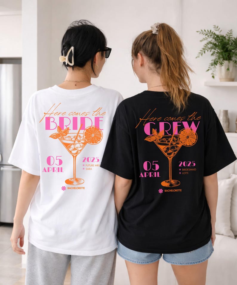 May include: Two oversized t-shirts, one white and one black, with matching graphics. The white shirt reads "Here comes the BRIDE" with a cocktail illustration and "05 APRIL 2025". The black shirt says "Here comes the CREW".