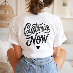 Könnte beinhalten: Weißes T-Shirt mit schwarzem Text "Customize Now" und einem kleinen schwarzen Herz.