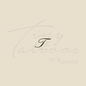 Può includere: Tatuaggio temporaneo con la lettera "T" in corsivo nero. Il tatuaggio misura 1,9 cm per 4,8 cm. Lo sfondo è beige chiaro con le parole "Tiny Tattoos" e "by tatteco" in corsivo.