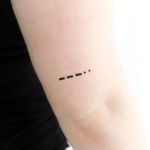以下が含まれることがあります： モース信号の小さなタトゥーをした腕のクローズアップ。