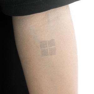 May include: A small, minimalist tattoo design featuring a series of wavy lines created with tiny dots.