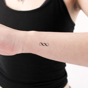 May include: A simple infinity symbol tattoo on a person's wrist.