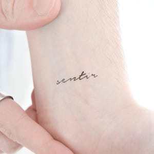 May include: A temporary tattoo with the word "sentir" written in cursive script.